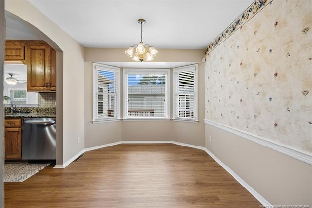 325 Hamilton St, Fayetteville, NC 28301 - unfurnished dining area with wood finished floors, wallpapered walls, a chandelier, and arched walkways
