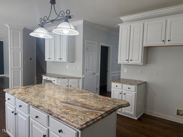 114 Council Gap Ct, Cary, NC 27513 - kitchen with light stone counters, ornamental molding, white cabinetry, dark wood-style floors, and a center island