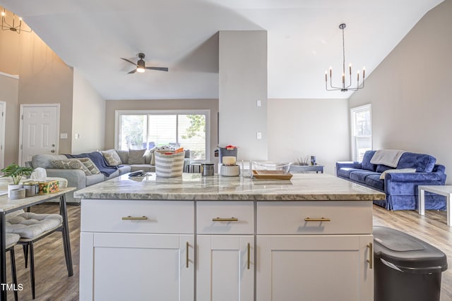 460 Dickens Dr, Raleigh, NC 27610 - kitchen featuring open floor plan, wood finished floors, a chandelier, white cabinets, and high vaulted ceiling