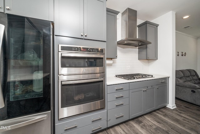 937 Baldwin Ridge Rd, Apex, NC 27523 - kitchen featuring appliances with stainless steel finishes, wall chimney range hood, gray cabinetry, dark wood-style flooring, and ornamental molding