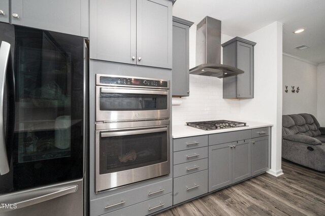 937 Baldwin Ridge Rd, Apex, NC 27523 - kitchen featuring appliances with stainless steel finishes, wall chimney exhaust hood, gray cabinetry, dark wood-style flooring, and backsplash