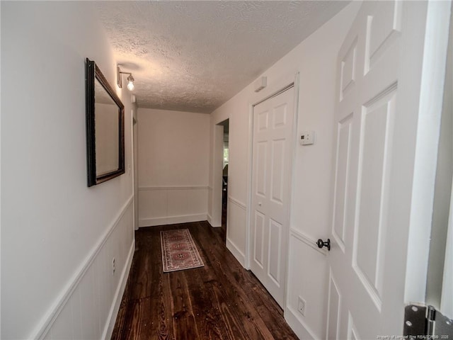 1554 Locklear Rd, Pembroke, NC 28372 - hall featuring dark wood finished floors, a textured ceiling, a decorative wall, and a wainscoted wall