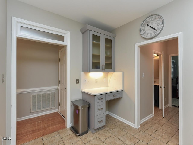 1005 Fairfax Woods Dr, Apex, NC 27502 - kitchen with gray cabinets, glass insert cabinets, light countertops, and built in study area