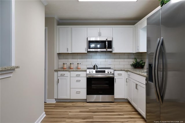 106 N 3rd St, Maxton, NC 28364 - kitchen with appliances with stainless steel finishes, white cabinets, light wood-type flooring, decorative backsplash, and crown molding
