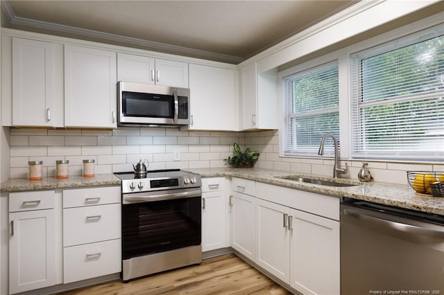 106 N 3rd St, Maxton, NC 28364 - kitchen with stainless steel appliances, crown molding, white cabinets, decorative backsplash, and light wood-style flooring