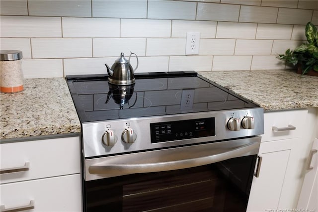 106 N 3rd St, Maxton, NC 28364 - kitchen view of electric range, tasteful backsplash, light stone counters, and white cabinets