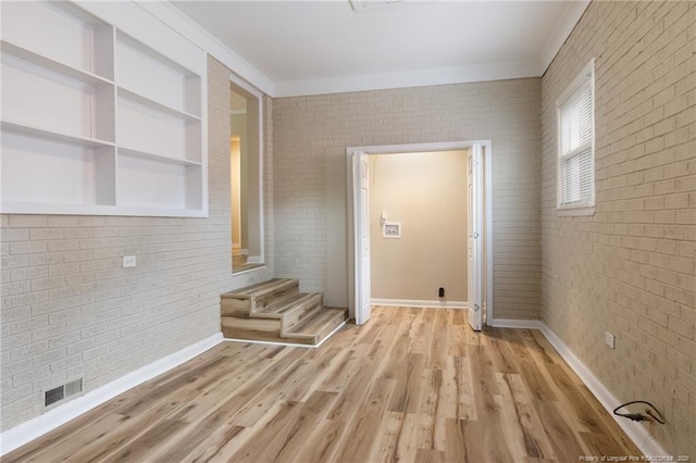 106 N 3rd St, Maxton, NC 28364 - unfurnished room featuring crown molding, brick wall, light wood-style flooring, and built in shelves