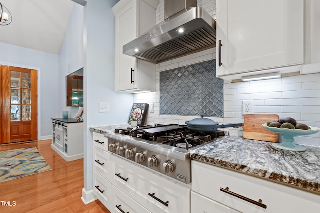 534 Siltstone Pl, Cary, NC 27519 - kitchen with ventilation hood, stainless steel gas stovetop, dark stone counters, light wood-style flooring, and white cabinets