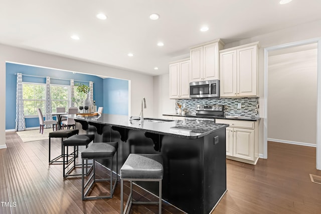 3504 Regent Pines Dr, New Hill, NC 27562 - kitchen with stainless steel appliances, a breakfast bar area, backsplash, a kitchen island with sink, and recessed lighting