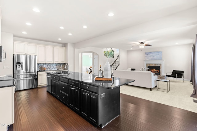 3504 Regent Pines Dr, New Hill, NC 27562 - kitchen with stainless steel appliances, dark cabinetry, a ceiling fan, arched walkways, and an island with sink