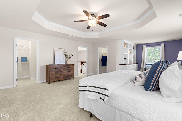 3504 Regent Pines Dr, New Hill, NC 27562 - bedroom featuring a walk in closet, a tray ceiling, a closet, ornamental molding, and a ceiling fan