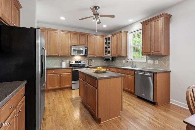 3921 Robins Nest Ln, Wake Forest, NC 27587 - kitchen featuring stainless steel appliances, light wood finished floors, dark countertops, a ceiling fan, and a center island