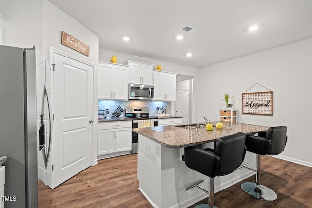 2730 Spring Valley Dr, Creedmoor, NC 27522 - kitchen featuring appliances with stainless steel finishes, backsplash, a breakfast bar area, wood finished floors, and light stone counters