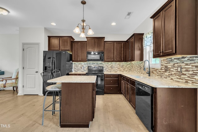 48 Manito Pl, Clayton, NC 27520 - kitchen featuring black appliances, dark brown cabinetry, light wood-style flooring, a kitchen island, and a kitchen bar