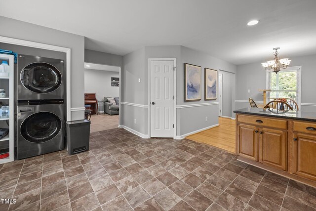 112 Autumn Ridge Dr, Knightdale, NC 27545 - laundry area with stacked washer / drying machine, a chandelier, recessed lighting, and dark stone finish floors