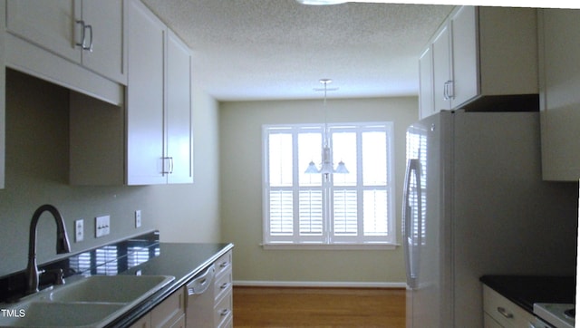 106 Knight Ct, Graham, NC 27253 - kitchen featuring white cabinets, wood finished floors, white appliances, dark countertops, and a textured ceiling