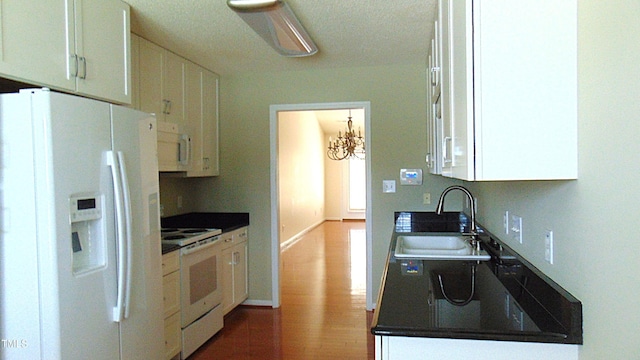 106 Knight Ct, Graham, NC 27253 - kitchen with white appliances, white cabinetry, wood finished floors, a chandelier, and dark countertops