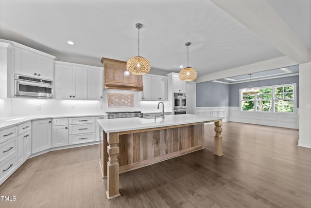 543 Allessandra Dr, Clayton, NC 27527 - kitchen featuring recessed lighting, custom range hood, light countertops, wainscoting, and a center island with sink