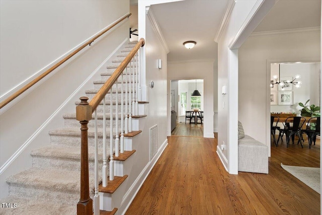 5833 Dahlberg Dr, Raleigh, NC 27603 - staircase featuring crown molding, wood finished floors, and a chandelier