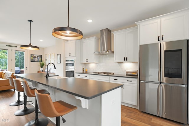 2055 Eva Pearl Dr, Apex, NC 27502 - kitchen with appliances with stainless steel finishes, wall chimney exhaust hood, dark countertops, a center island with sink, and recessed lighting