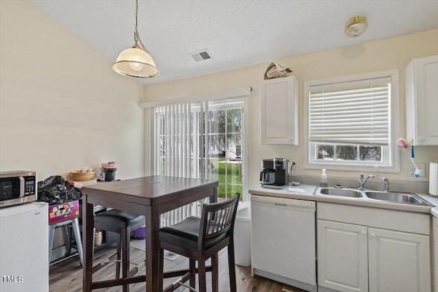 5104 Parkerwood Dr, Knightdale, NC 27545 - kitchen with dishwasher, stainless steel microwave, white cabinetry, light wood-type flooring, and light countertops