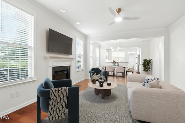 9201 Wooden Rd, Raleigh, NC 27617 - living room featuring ornamental molding, wood finished floors, a fireplace, a ceiling fan, and a chandelier