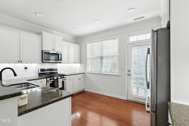 9201 Wooden Rd, Raleigh, NC 27617 - kitchen featuring stainless steel appliances, white cabinets, tasteful backsplash, wood-type flooring, and dark stone counters