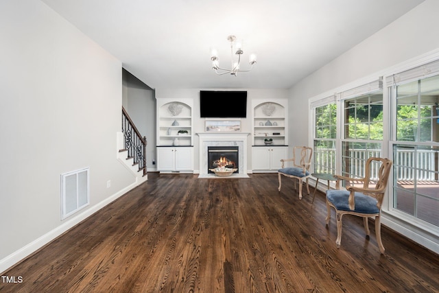 3811 Cottonwood Dr, Durham, NC 27705 - living area featuring built in shelves, dark wood-style floors, a fireplace with flush hearth, a chandelier, and stairway