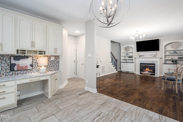 3811 Cottonwood Dr, Durham, NC 27705 - kitchen featuring a chandelier, built in study area, open floor plan, backsplash, and white cabinetry