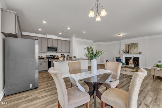 3505 Triad Ct, Raleigh, NC 27604 - dining space with ornamental molding, a lit fireplace, a chandelier, recessed lighting, and light wood-style floors