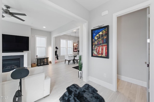 1008 Whistler St, Durham, NC 27713 - living room with a chandelier, light wood-style floors, a ceiling fan, a glass covered fireplace, and recessed lighting