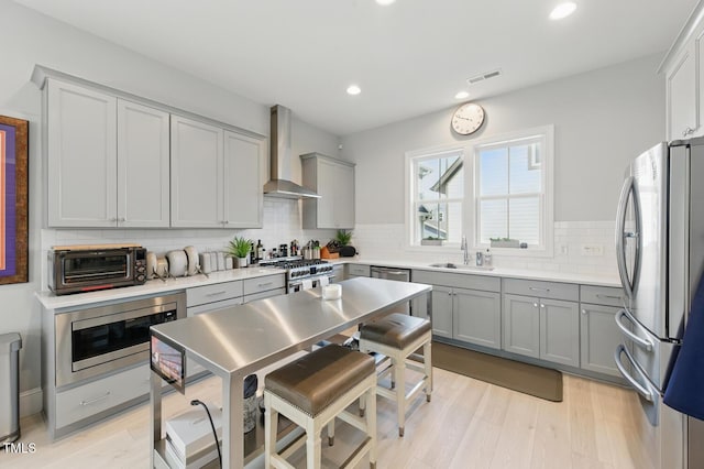 1008 Whistler St, Durham, NC 27713 - kitchen featuring wall chimney range hood, stainless steel appliances, gray cabinetry, light wood-style floors, and recessed lighting