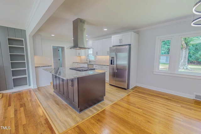 303 Winhaven St, Roxboro, NC 27573 - kitchen featuring appliances with stainless steel finishes, island exhaust hood, crown molding, white cabinetry, and light wood-style floors