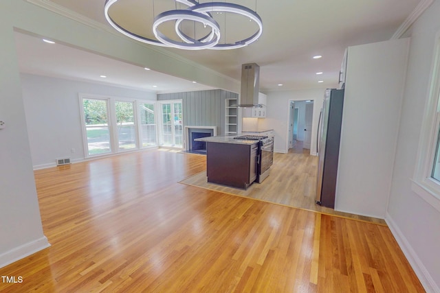 303 Winhaven St, Roxboro, NC 27573 - kitchen featuring island exhaust hood, appliances with stainless steel finishes, open floor plan, light wood finished floors, and ornamental molding