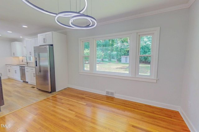 303 Winhaven St, Roxboro, NC 27573 - kitchen with stainless steel appliances, light wood-type flooring, white cabinetry, light countertops, and ornamental molding