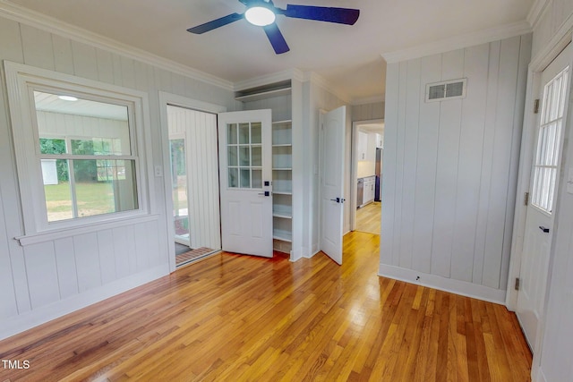 303 Winhaven St, Roxboro, NC 27573 - empty room with light wood-type flooring, healthy amount of natural light, crown molding, ceiling fan, and wood walls