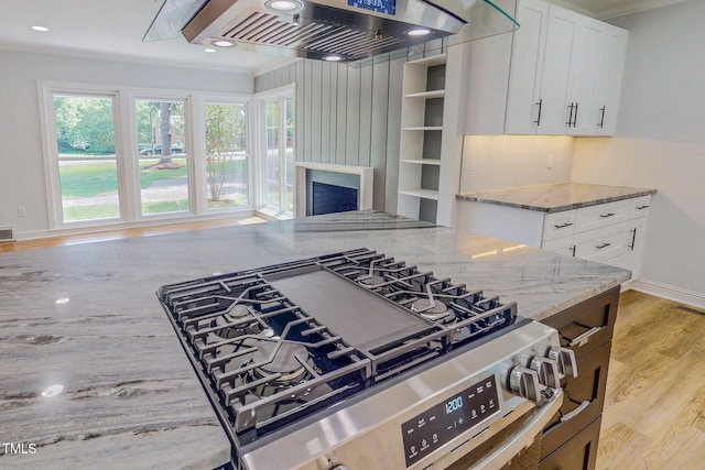 303 Winhaven St, Roxboro, NC 27573 - kitchen featuring stainless steel gas range, ventilation hood, light stone counters, light wood-style flooring, and white cabinets