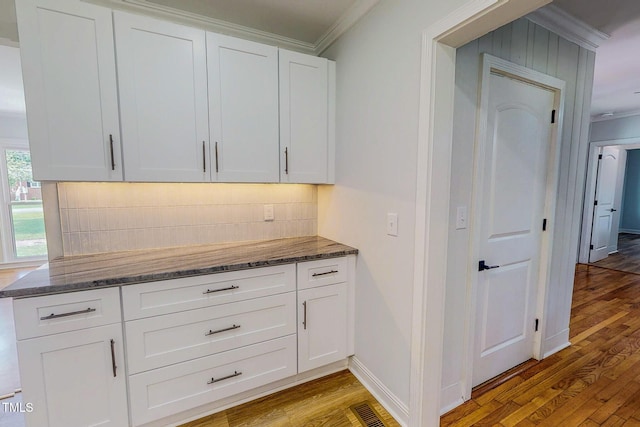 303 Winhaven St, Roxboro, NC 27573 - kitchen with ornamental molding, light wood finished floors, decorative backsplash, dark stone countertops, and white cabinets
