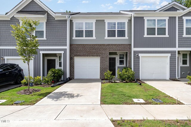 2050 Trailside Dr, Durham, NC 27704 - townhome / multi-family property featuring driveway, brick siding, a front yard, and an attached garage