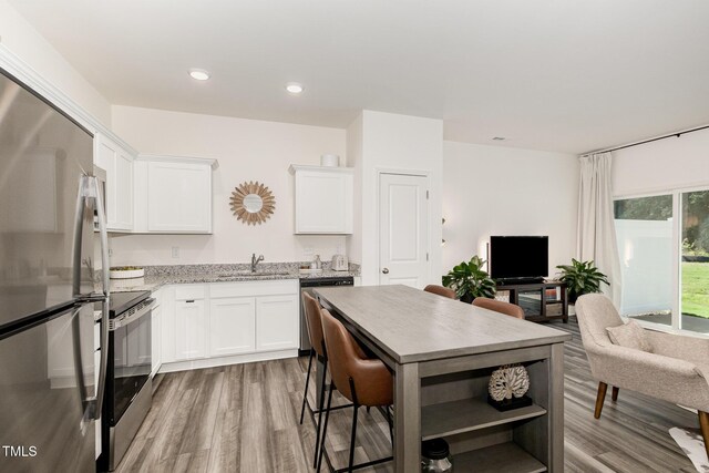 2050 Trailside Dr, Durham, NC 27704 - kitchen with appliances with stainless steel finishes, wood finished floors, open shelves, white cabinets, and light stone counters