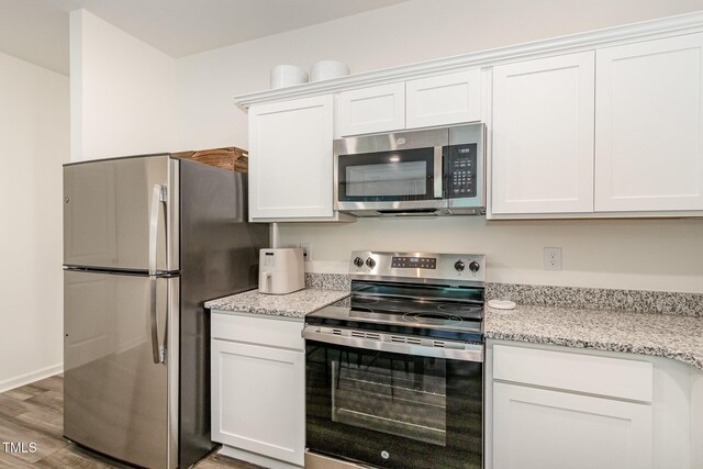 2050 Trailside Dr, Durham, NC 27704 - kitchen featuring stainless steel appliances, white cabinetry, wood finished floors, and light stone countertops