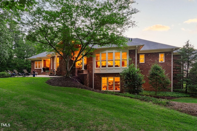 114 Kendleton Pl, Cary, NC 27518 - back of property at dusk featuring brick siding, a lawn, and a patio area