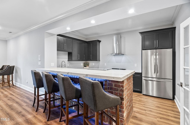 114 Kendleton Pl, Cary, NC 27518 - kitchen with freestanding refrigerator, wall chimney range hood, light wood finished floors, a kitchen breakfast bar, and a peninsula