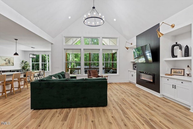 88 Priscilla Ln, Fuquay Varina, NC 27526 - living area with a chandelier, high vaulted ceiling, a glass covered fireplace, and light wood-style flooring