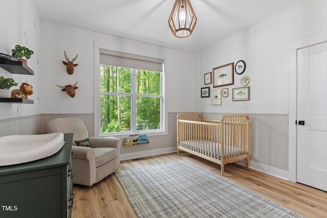 88 Priscilla Ln, Fuquay Varina, NC 27526 - bedroom with a wainscoted wall, a nursery area, and light wood-style floors