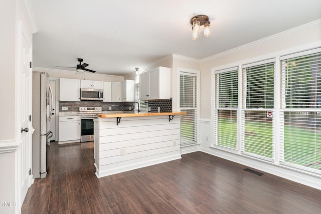 1006 Mingo Pl, Knightdale, NC 27545 - kitchen with appliances with stainless steel finishes, butcher block countertops, dark wood-style flooring, decorative backsplash, and a peninsula