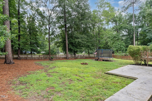 1006 Mingo Pl, Knightdale, NC 27545 - fenced backyard featuring a trampoline, a patio, an outdoor fire pit, and view of wooded area