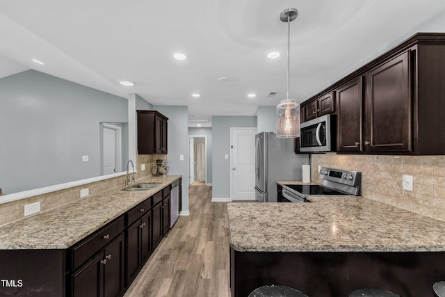39 All Aboard Cir, Willow Springs, NC 27592 - kitchen with appliances with stainless steel finishes, a peninsula, dark brown cabinets, light wood-style flooring, and decorative backsplash