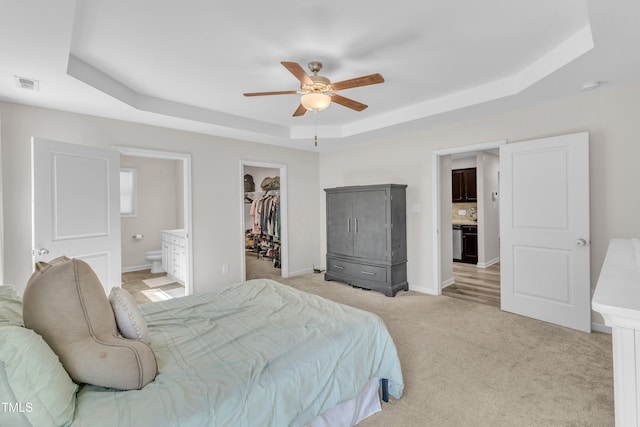 39 All Aboard Cir, Willow Springs, NC 27592 - bedroom featuring a tray ceiling, a walk in closet, light carpet, ensuite bathroom, and a ceiling fan