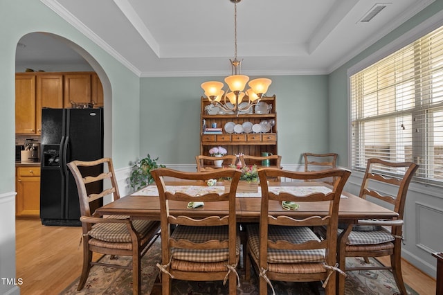 5216 Marcella Ct, Durham, NC 27707 - dining room featuring arched walkways, a tray ceiling, a chandelier, light wood-type flooring, and ornamental molding